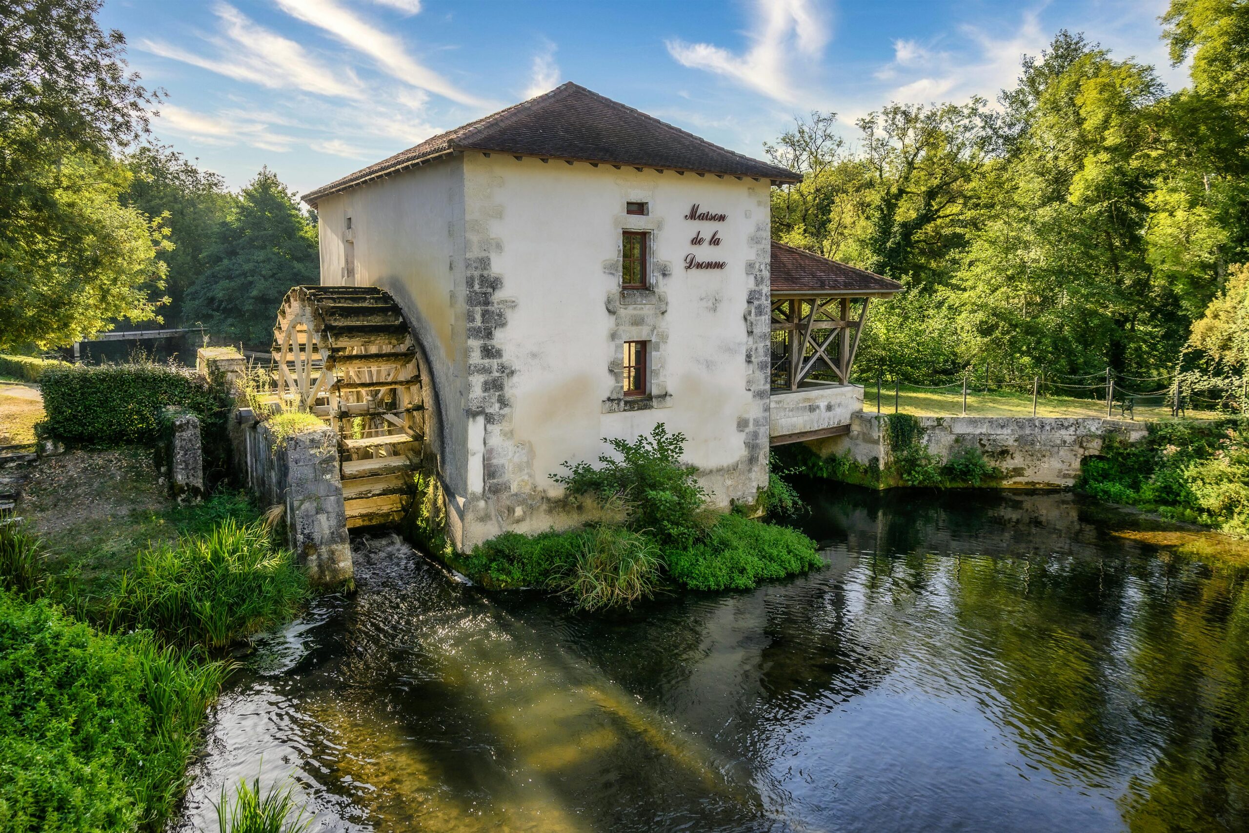 Picturesque watermill by a pond in Tocane-Saint-Apre, France surrounded by lush greenery.